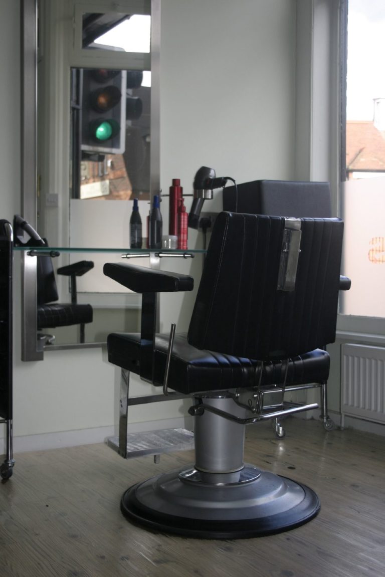 Barber Chairs A Barber chair in front of a mirror with hair products on the counter.